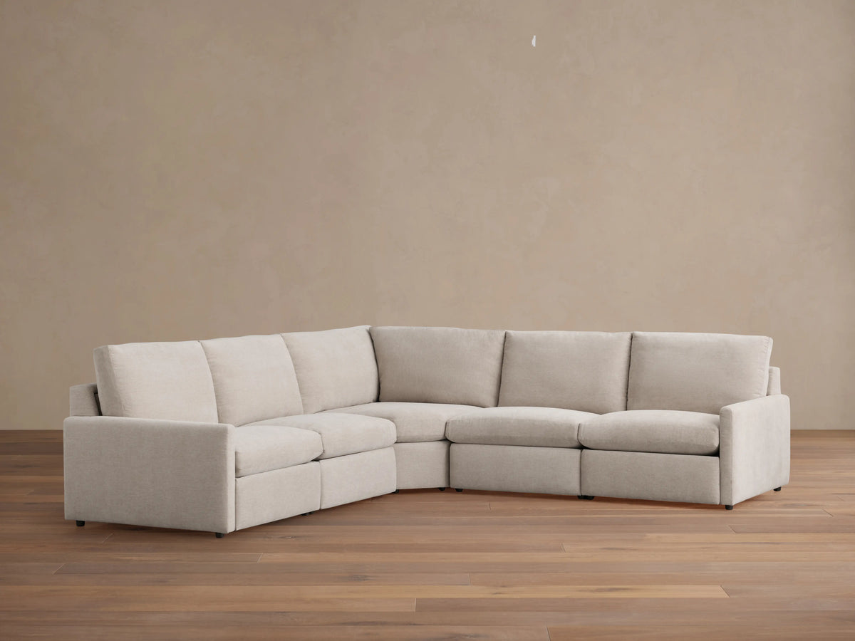 Kipton Five-Piece Motion Corner Sectional in beige fabric on wooden floor, featuring slim arms and plush backrests.