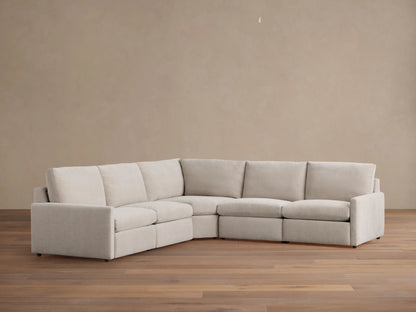 Kipton Five-Piece Motion Corner Sectional in beige fabric on wooden floor, featuring slim arms and plush backrests.