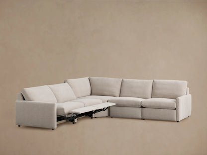 Alt text: The Kipton Five-Piece Motion Corner Sectional in light gray fabric is shown from a rear angle, highlighting its modular design and slim arms against a neutral background.