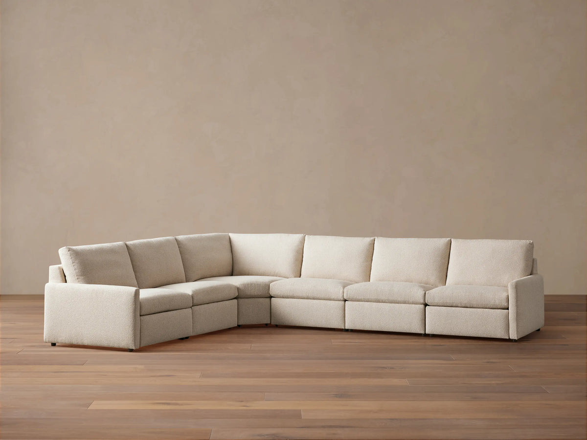 High-angle view of a light beige Kipton Slim Arm Six-Piece Motion Sectional in an L-shape, with one footrest extended.