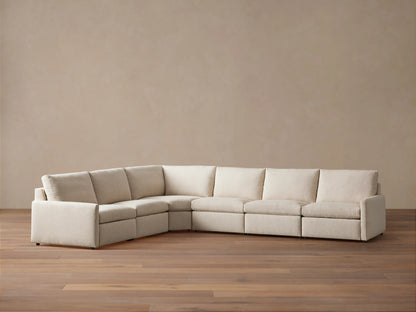 High-angle view of a light beige Kipton Slim Arm Six-Piece Motion Sectional in an L-shape, with one footrest extended.