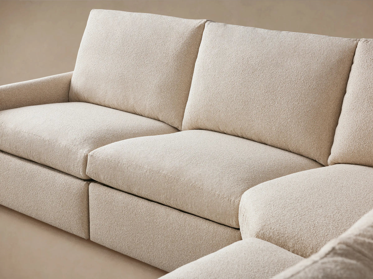 Close-up of the Kipton Six-Piece Motion Sectional's slim arm in textured beige fabric, featuring a two-button motion control.