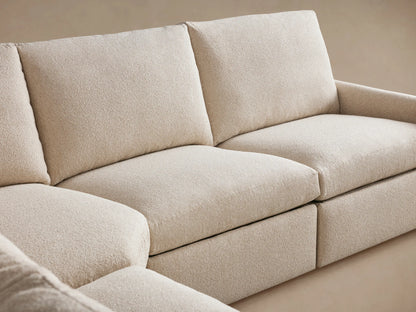 Kipton Slim Arm Six-Piece Motion Sectional. L-shaped, light beige textured fabric sofa on wood floor, against a tan wall.