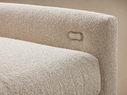 Close-up of a Kipton Slim Arm Motion Sectional's light beige textured fabric, showing multiple cushions and a corner.