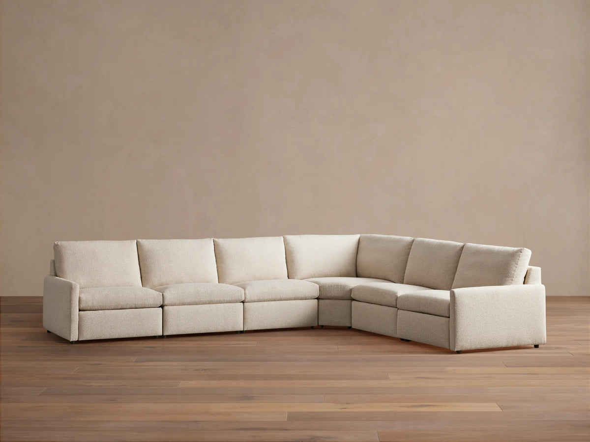 High-angle view of a beige Kipton Slim Arm Six-Piece Motion Sectional in an L-shape, with one footrest extended.