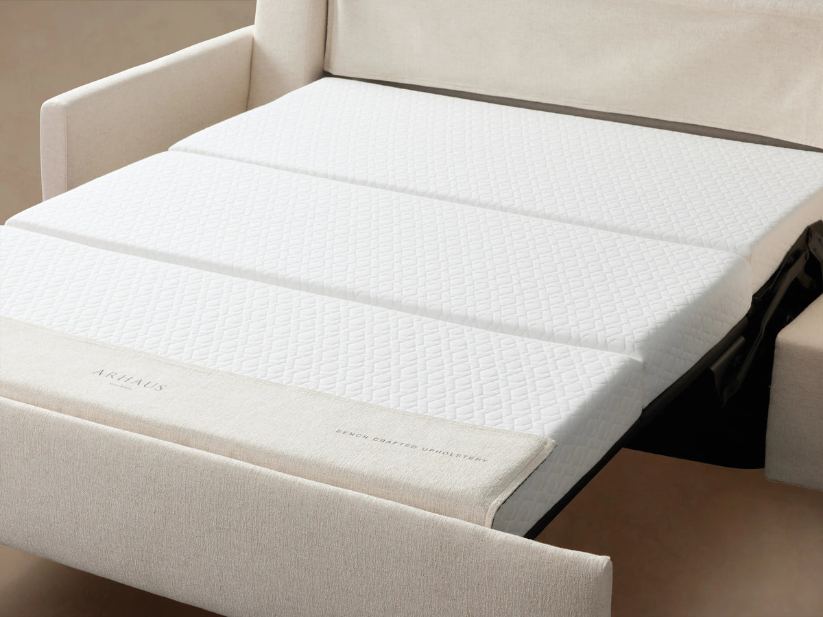 Kipton Luxury Sleeper Sofa in cream fabric with straight arms, plush seat and back cushions on wooden floor, against a beige background.