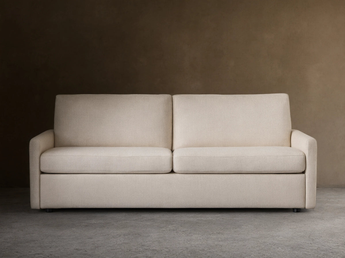 Kipton Luxury Sleeper Sofa in beige fabric, shown from the front with plush seat and back cushions, set on a wooden floor.