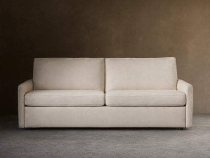 Kipton Luxury Sleeper Sofa in beige fabric, shown from the front with plush seat and back cushions, set on a wooden floor.