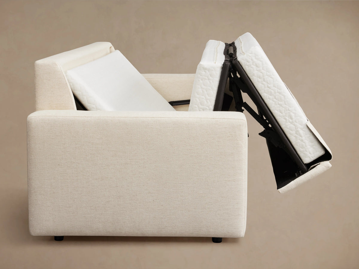 Kipton Wide Arm Luxury Sleeper Sofa in beige fabric, features wide arms, rectangular back cushions, and a sleek wood floor setting.