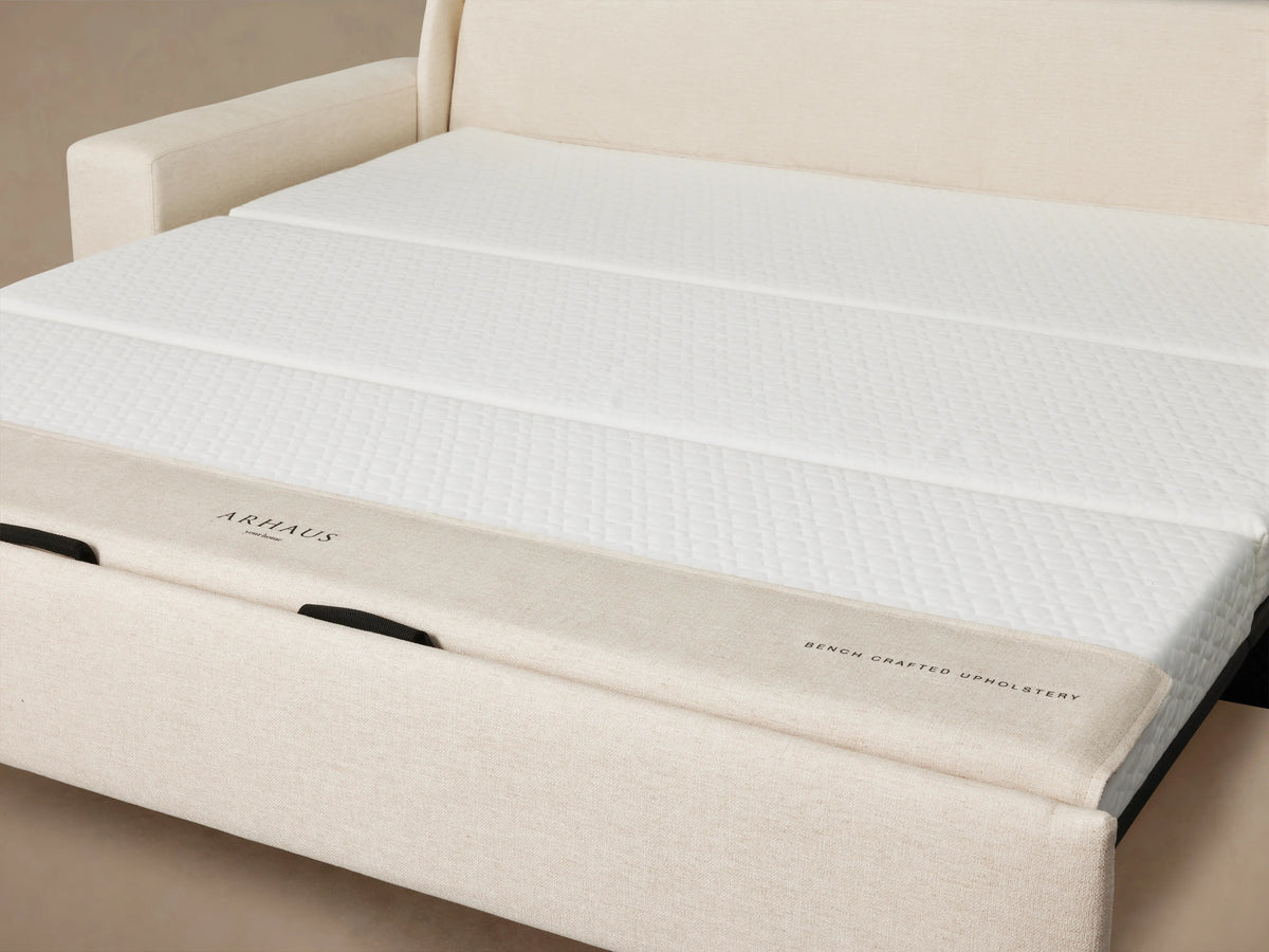 Back view of the Kipton Wide Arm Luxury Sleeper Sofa in beige fabric. Features wide arms and a rectangular shape set against a plain background.