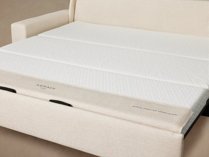 Back view of the Kipton Wide Arm Luxury Sleeper Sofa in beige fabric. Features wide arms and a rectangular shape set against a plain background.