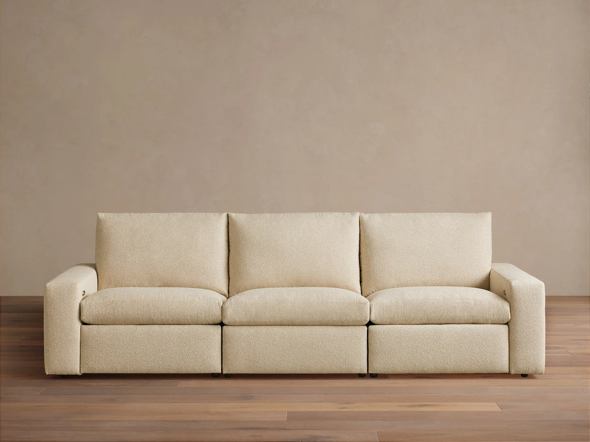 Kipton Wide Arm Three-Piece Motion Modular Sofa in beige fabric, showing three seats and wide arms on a wooden floor.