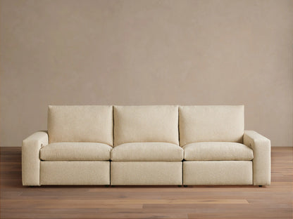 Kipton Wide Arm Three-Piece Motion Modular Sofa in beige fabric, showing three seats and wide arms on a wooden floor.