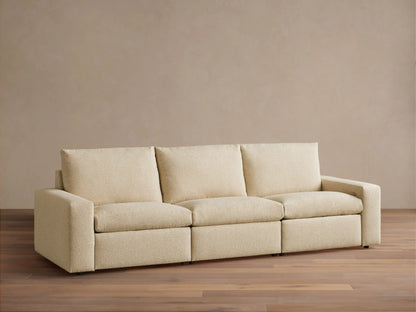 Kipton Wide Arm Three-Piece Motion Modular Sofa in beige fabric, showing three seats and wide arms on a wooden floor.