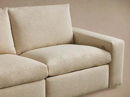 Close-up of the Kipton Wide Arm Three-Piece Motion Modular Sofa in beige fabric, showing wide arm with a silver two-button motion control.
