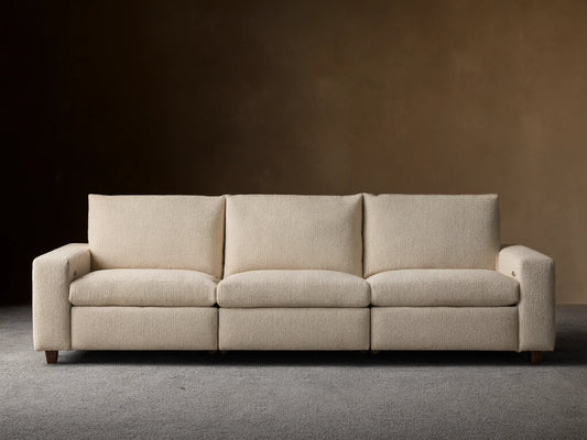 Kipton Wide Arm Three-Piece Motion Modular Sofa in beige fabric, showing three seats and wide arms on a wooden floor.