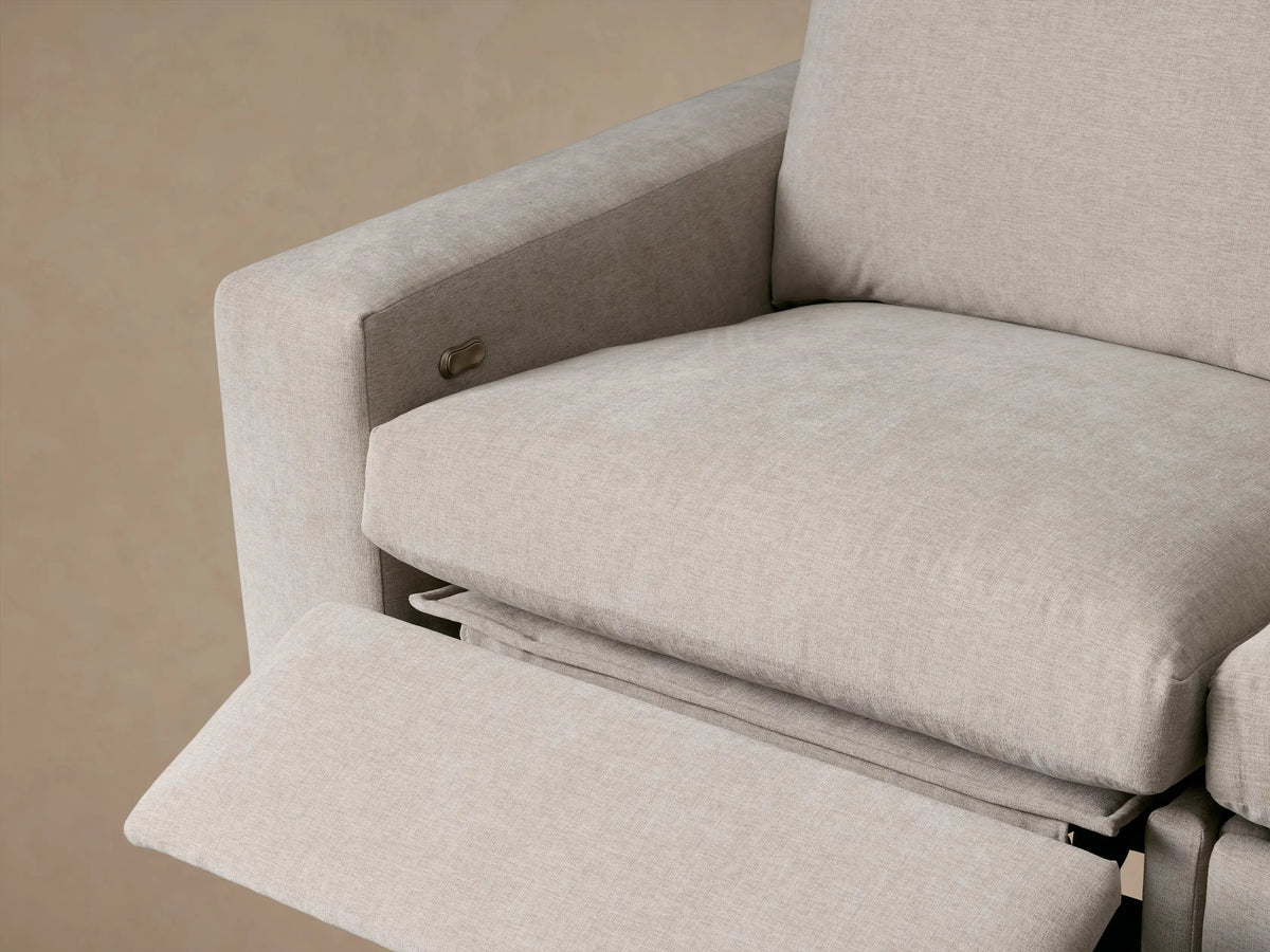 Kipton Wide Arm Four-Piece Motion Sectional, light beige L-shaped sofa with plush cushions and wide arms, on wood floor.
