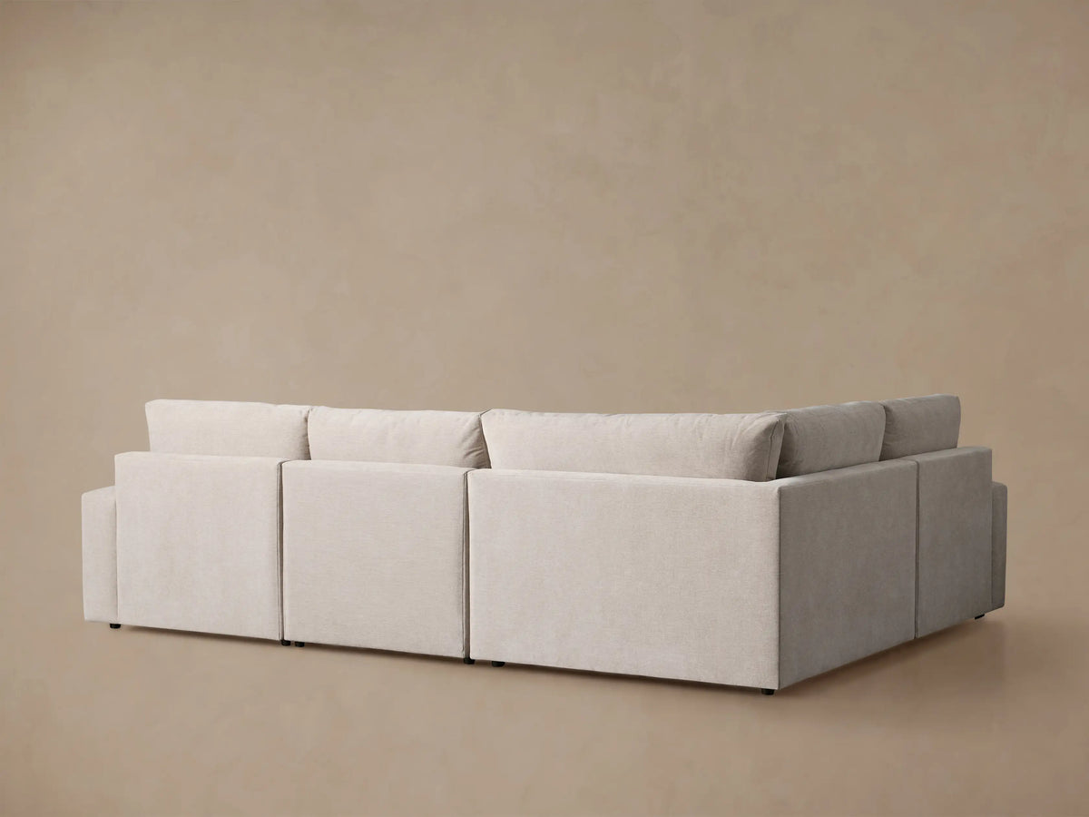 Close-up of Kipton Wide Arm Motion Sectional in light beige fabric, showing extended footrest & arm with recline button.