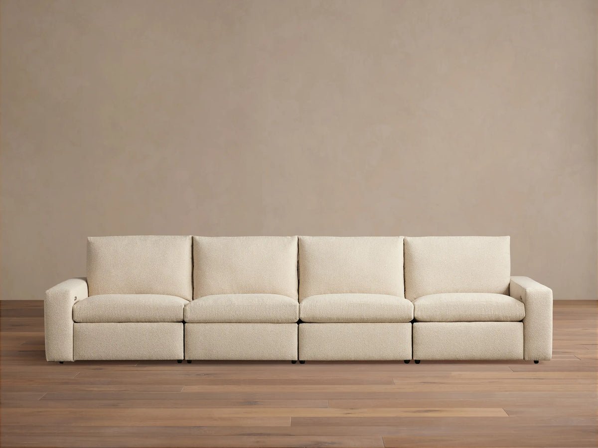 Kipton Wide Arm Four-Piece Motion Modular Sofa in beige fabric on wooden floor, straight view, with wide arms and four cushioned seats.