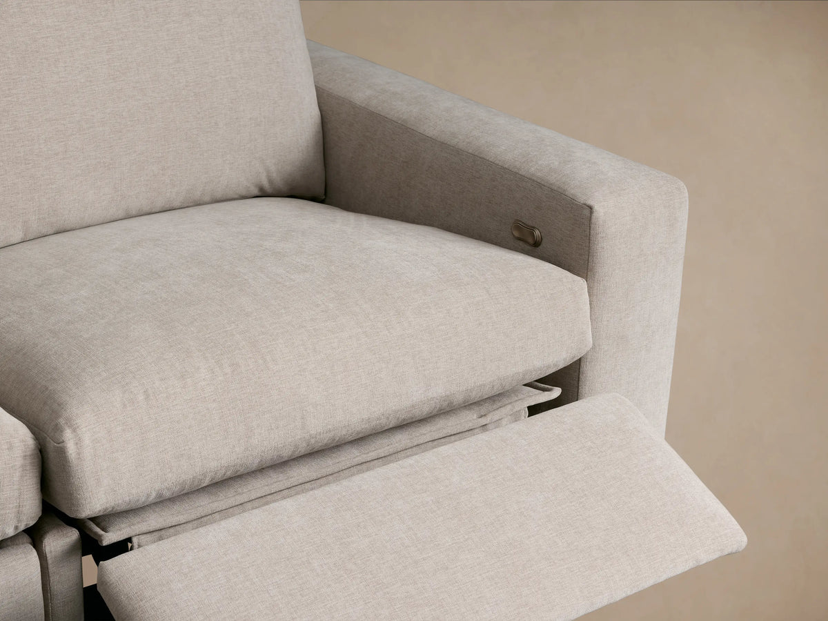 Light beige Kipton Wide Arm Four-Piece Motion Sectional, L-shaped, upholstered in textured fabric, against a neutral wall.