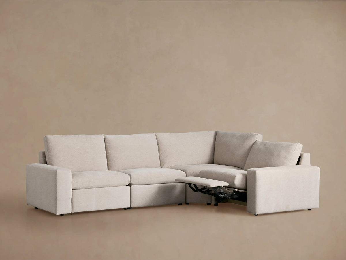 Light beige Kipton Wide Arm Four-Piece Motion Sectional, L-shaped. Two footrests are extended, showing black metal mechanisms.