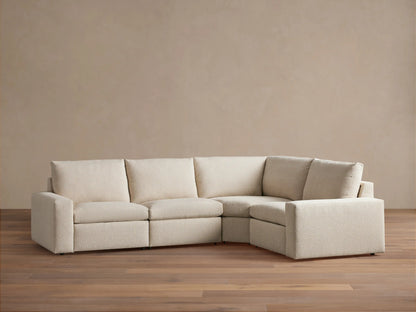 Kipton Wide Arm Four-Piece Motion Sectional in beige fabric, featuring wide arms, tufted backrests, and a corner configuration on a wooden floor.