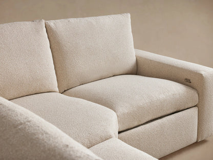 Close-up view of the Kipton Wide Arm Sectional's beige textured fabric. Features a sleek two-button metal motion control on the armrest.