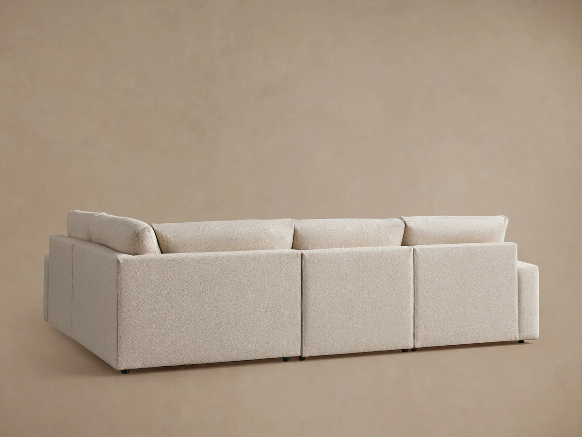 Alt text: Kipton Wide Arm Four-Piece Motion Sectional in light beige fabric, featuring wide armrests and plush cushions, angled view.