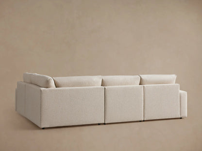 Alt text: Kipton Wide Arm Four-Piece Motion Sectional in light beige fabric, featuring wide armrests and plush cushions, angled view.