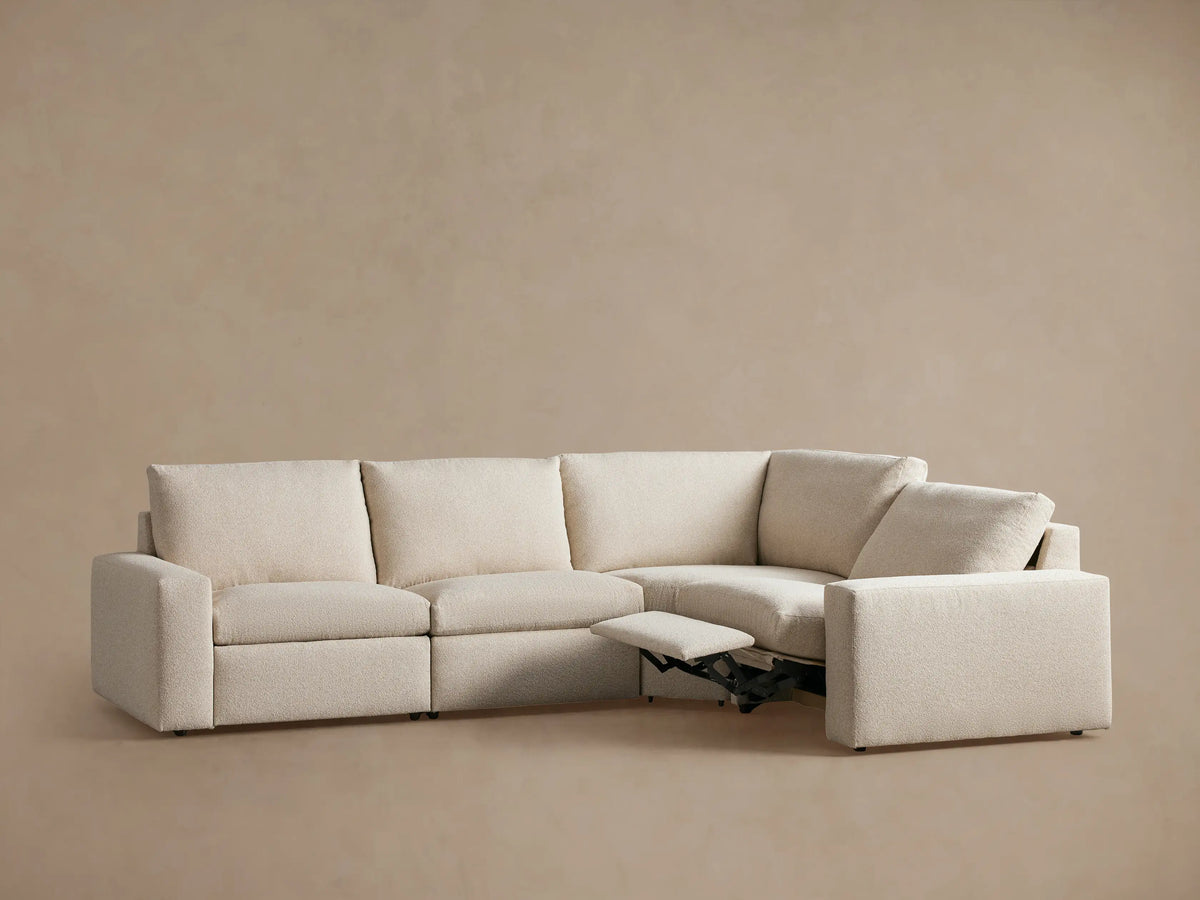 Kipton Wide Arm Four-Piece Motion Sectional in beige fabric, shown in an L-shape. Two seats have extended footrests, with wide arms and cushioned backs.