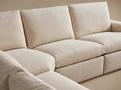 Beige Kipton Wide Arm Five-Piece Motion Corner Sectional with plush cushions and wide armrests, showing a close-up of textured upholstery.