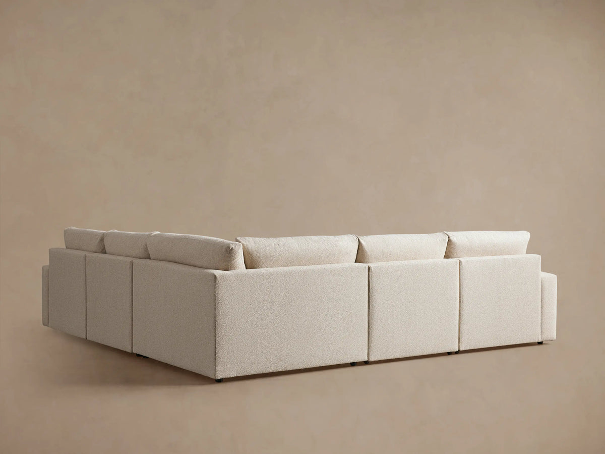 Kipton Wide Arm Five-Piece Motion Corner Sectional in cream color, showing the back and side view with wide arms and cushioned backrests against a neutral background.