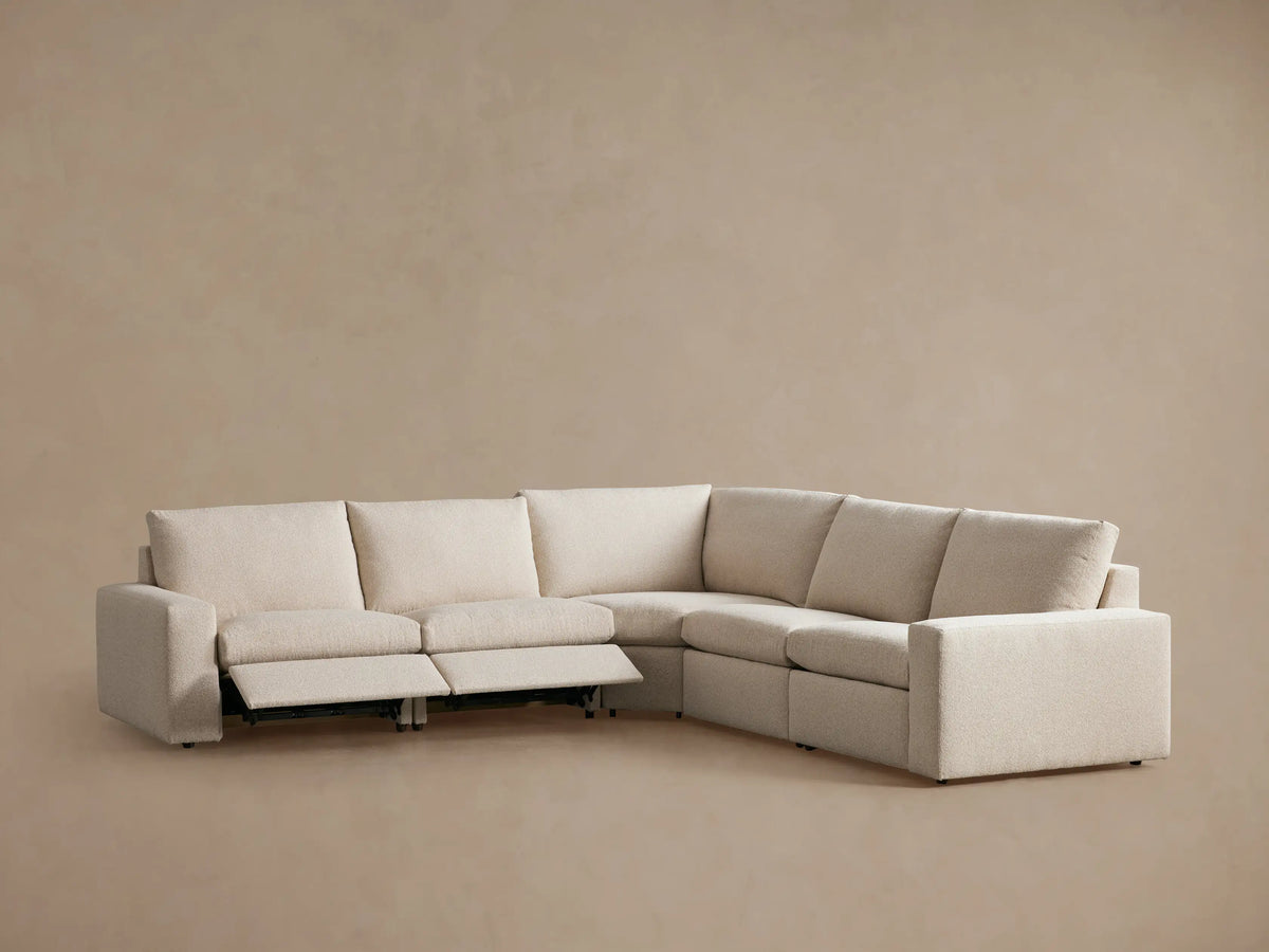 Kipton Wide Arm Five-Piece Motion Corner Sectional in beige fabric with wide armrests, partial recline on left, set against a plain background.