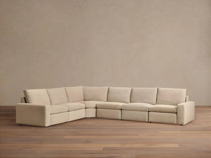 Kipton Wide Arm Six Piece Motion Sectional in beige fabric, showing wide armrests; set against a wooden floor and neutral wall.