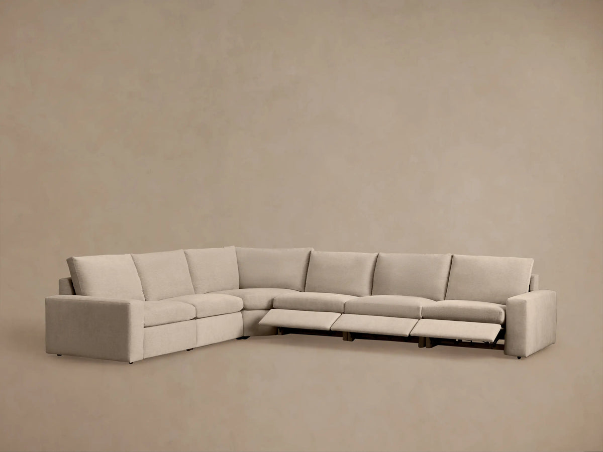 Kipton Wide Arm Six Piece Motion Sectional in beige fabric; L-shaped, wide arms, plush cushions; set in a modern room.