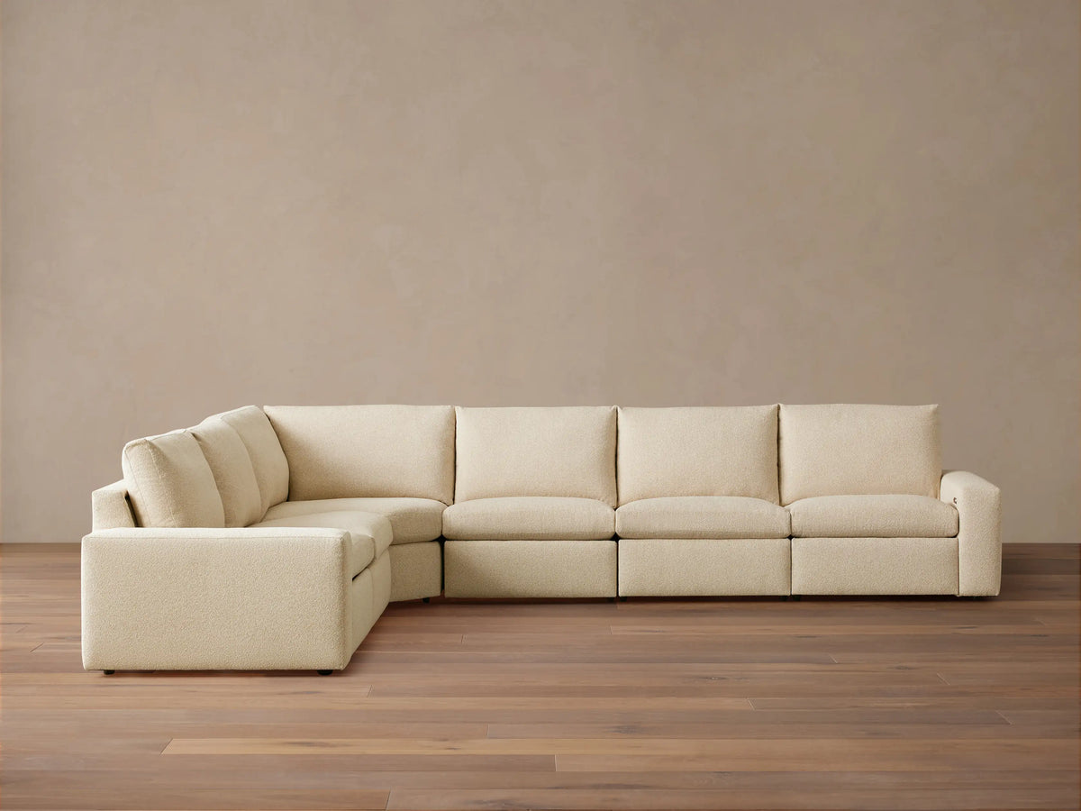 Kipton Wide Arm Six Piece Motion Sectional in beige fabric, L-shaped with wide arms, set on wooden floor against a plain backdrop.