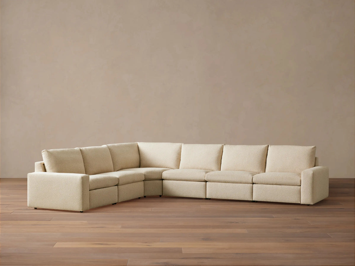 Kipton Wide Arm Six Piece Motion Sectional in beige fabric, L-shaped with wide arms, set on wooden floor against a plain backdrop.