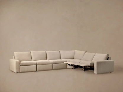 Back and side view of an L-shaped Kipton Wide Arm Six Piece Motion Sectional, upholstered in light beige fabric, against a neutral wall.