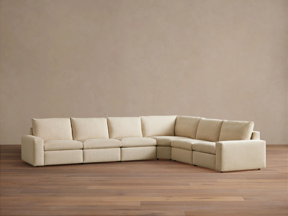 Kipton Wide Arm Six Piece Motion Sectional in beige fabric on wooden floor, featuring six seats in an L-shape with wide arms and plush cushions.