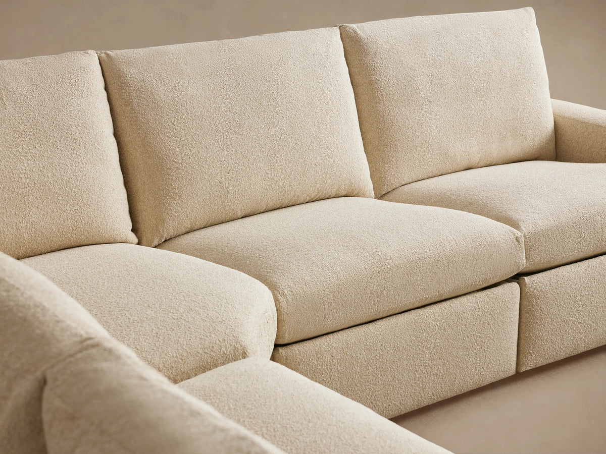 Beige textured fabric close-up of Kipton Wide Arm Sectional armrest, showcasing a two-button motion control feature on its side.