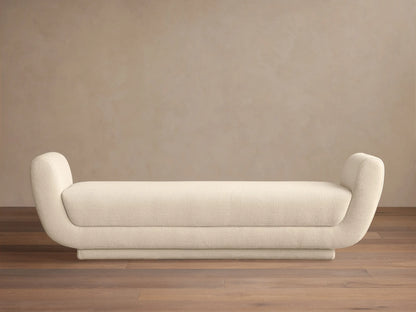 Fontana Bench, long cream upholstered bench with sleek, rounded ends, centered on a wood floor against a neutral background.