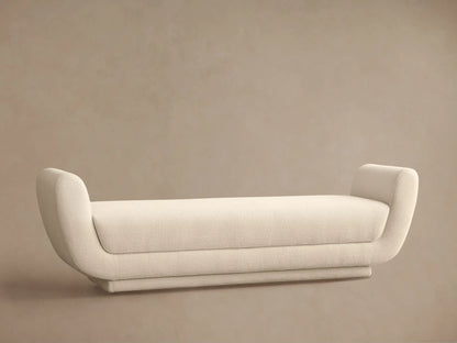 Fontana Bench, long cream upholstered bench with sleek, rounded ends, centered on a wood floor against a neutral background.