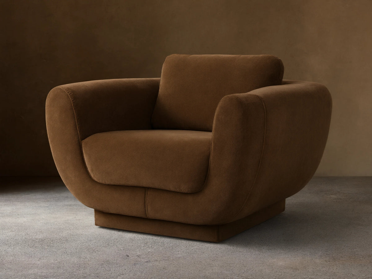 Fontana Swivel Chair, curvy brown fabric armchair with rounded arms, deep seat, and back cushion, on a wooden floor.