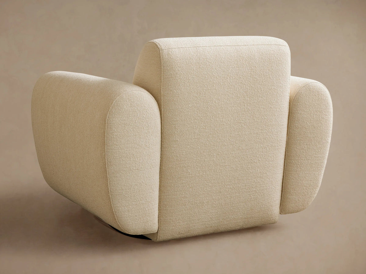 Angled close-up of a cream Gianni Swivel Chair. Features textured boucl?? fabric, rounded backrest & armrest.