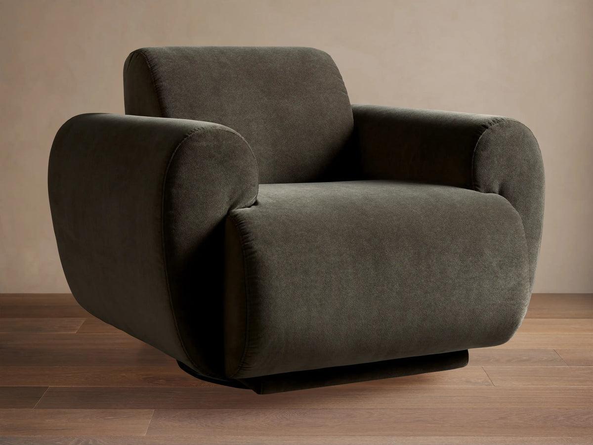 Gianni Swivel Chair: Modern, dark olive green velvet swivel armchair with plump, rounded arms & back, on a hardwood floor.