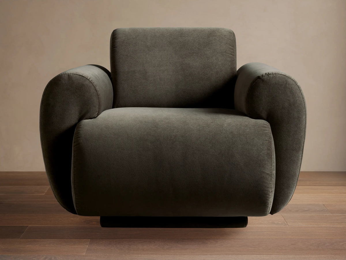 Gianni Swivel Chair: Modern, dark olive green velvet swivel armchair with plump, rounded arms & back, on a hardwood floor.