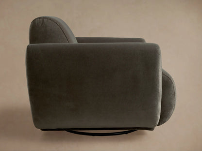 Front view of a plush, dark gray Gianni Swivel Chair with rounded arms and a low profile, on a warm wooden floor.