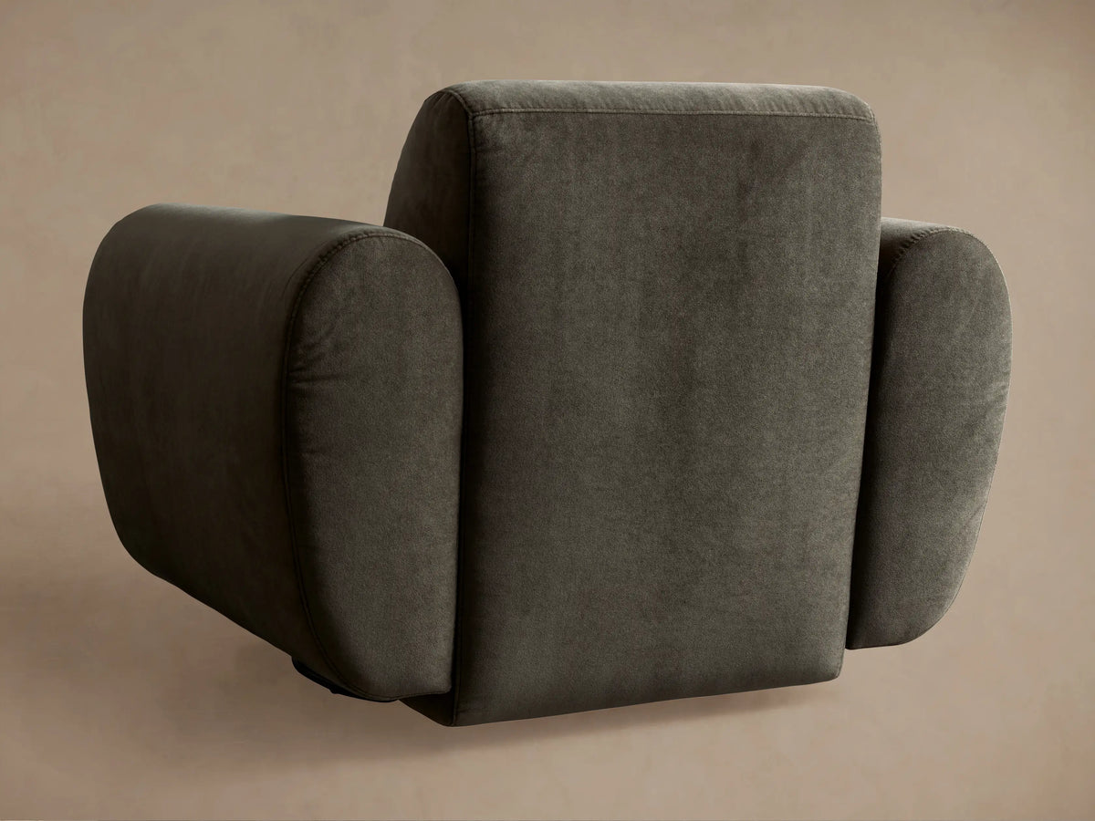 Close-up of a dark gray Gianni Swivel Chair in soft, plush fabric, highlighting its curved armrest and backrest detail.