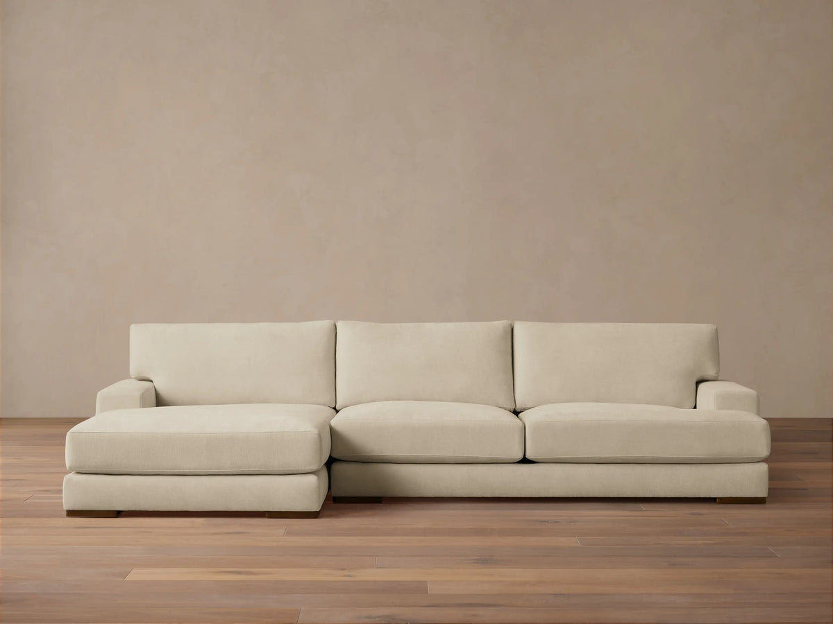 Norwalk Two-Piece Chaise Sectional in beige fabric, featuring a left-facing chaise and three-seat sofa on wooden floor, against a neutral wall.