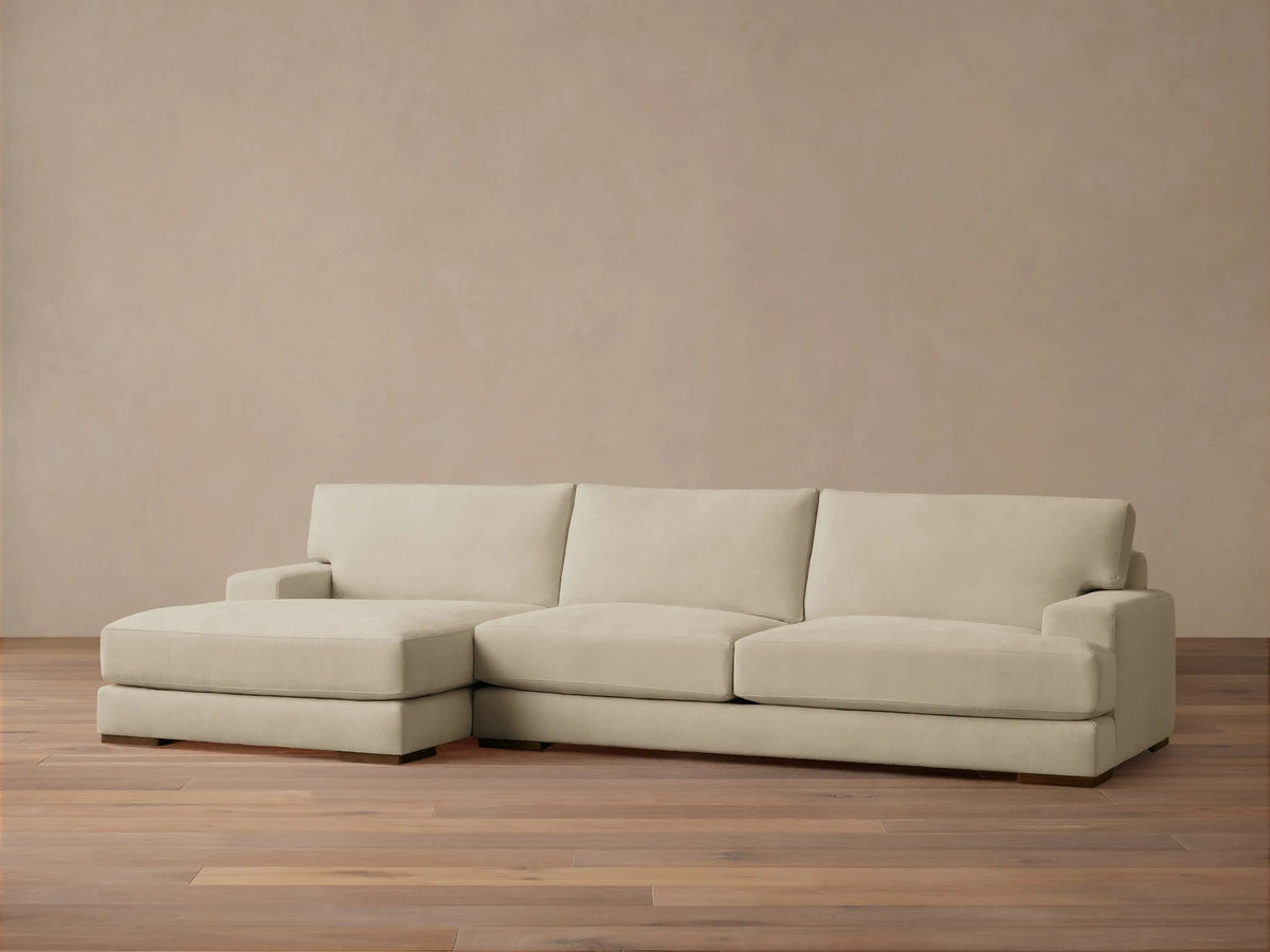 Norwalk Two-Piece Chaise Sectional in beige fabric, featuring a left-facing chaise and three-seat sofa on wooden floor, against a neutral wall.